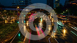 Dusk-to-night timelapse of modern Asian city intersection. Car light trails, urban lights, ads, people cross streets