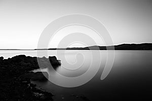 Dusk on Trasimeno lake Umbria, with rocks in the foreground, p