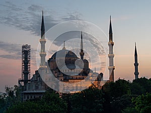 Dusk view of the floodlit blue mosque exterior in istanbul, turkey- mahya says infak bereket getirir in english it means