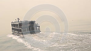 Dusk view of moving travel cruise ship and following water vessels behind running sea gull at deep sea