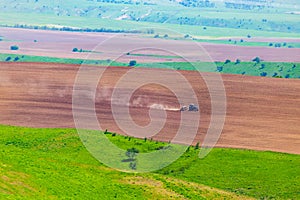 Dust from a tractor working in a field in spring