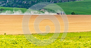 Dust from a tractor working in a field in spring