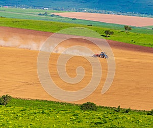 Dust from a tractor working in a field in spring