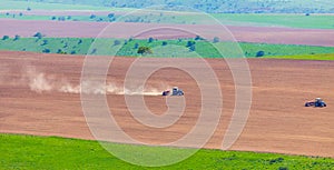 Dust from a tractor working in a field in spring