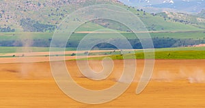 Dust from a tractor working in a field in spring