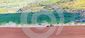 Dust from a tractor working in a field in spring