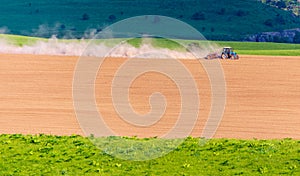 Dust from a tractor working in a field in spring