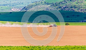 Dust from a tractor working in a field in spring