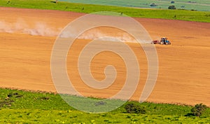 Dust from a tractor working in a field in spring