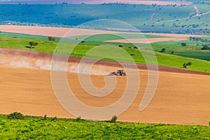 Dust from a tractor working in a field in spring