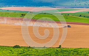 Dust from a tractor working in a field in spring