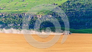 Dust from a tractor working in a field in spring