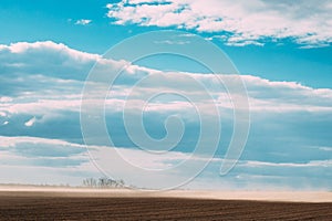 Dust Wind At Field. Dust Cloud On Agricultural Field. Bold Blue Color Sky Background. Spring Dust Storm. Agricultural