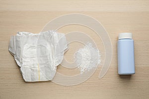 Dusting powder and diaper on wooden background, flat lay. Baby care products