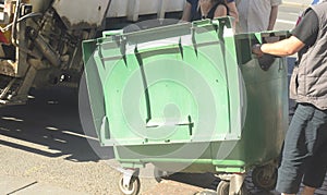 Dustman worker is moving empty garbage container from truck