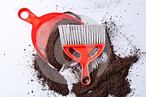 Dustpan, broom and soil on the floor.