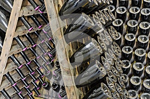 Dusty bottles with brut sparkling wine on wooden rack photo