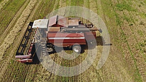 Dusty combine harvester with a working thresher and reel is deployed to perform the process and unload the hopper