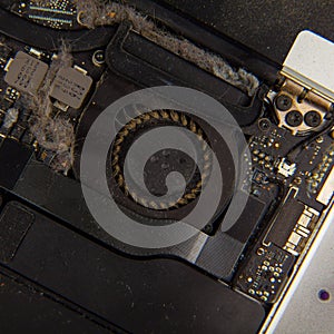 Dusty cooling fan inside laptop disassembled for cleaning closeup