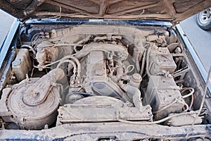 Dusty details of a flat-four boxer car engine compartment under the open hood. Alternator and intake manifold. Closeup