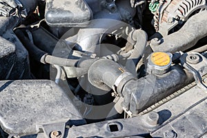 Dusty details of a flat-four boxer car engine compartment under the open hood. Car radiator cap and hose