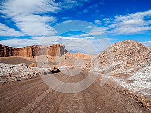 Dusty dirt road surrounded by dirt mounds and cliffs