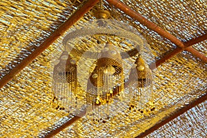 Dusty old street lamp in Arabic style, hanging from the ceiling under a wicker wooden canopy