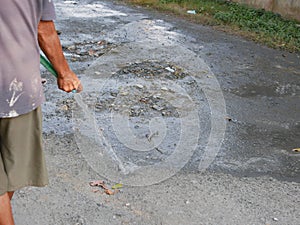 A dusty road being watered preventing the dust to be kicked up by vehicles that pass over the dirt road