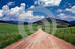 Dusty road through green hilly pasture land