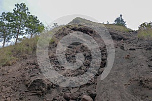 Dusty trail with lava slag and rocks to the top of Batur volcano. Road Extreme terrain to the mountain. Footpath around crater