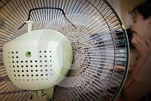 Dusty or unclean portable fan with blurred girl working at table