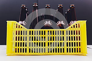 Dusty vintage yellow beer crate with empty brown beer bottles on white background.