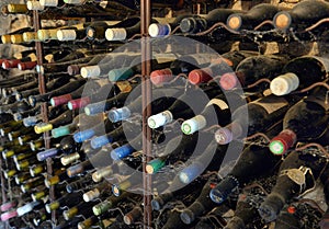 Dusty wine bottles in a wine cellar. Wine bottles stacked up in old wine cellar close-up background