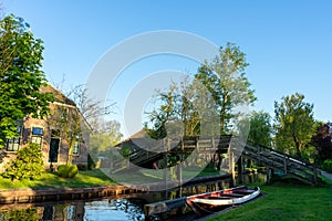 Dutch architecture house by the canal with a red boat and a wooden bridge