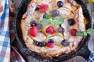 Dutch baby pancake with apples and cinnamon in a pan on a table. Top view