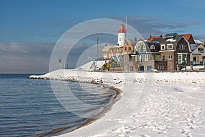 Dutch beach covered with snow and view at lighthouse Urk photo