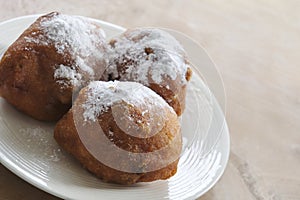 Dutch doughnuts with currants and powdered sugar on a white plate