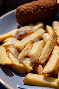 Dutch fast food, deep fried croquettes filled with ground beef meat and french fried potatoes chips served with green salad, close