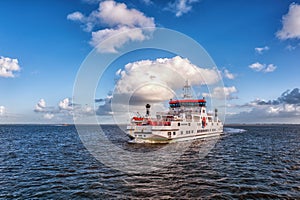 Dutch ferry boat at Wadden Sea navigating with low tide through small channels between sandbanks