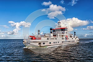 Dutch ferry boat at Wadden Sea navigating with low tide through small channels between sandbanks