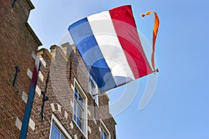 A dutch flag with streamer on the facade of a house