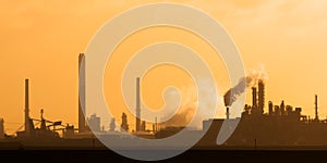 Dutch industrial plant with chimneys and windmill during sunset in Europoort, Rotterdam