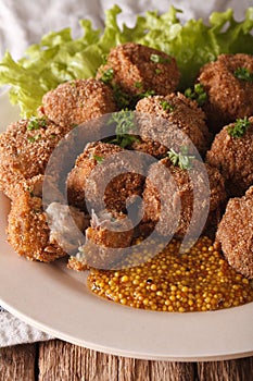 Dutch meat balls with mustard Bitterballen close-up on a plate.