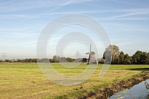 Dutch mill in the countryside in the Netherlands surrounded by pasture, blue sky