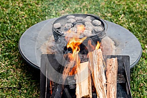 Dutch oven camp cooking with coal briquettes beads on top. Campfire