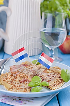 Dutch pancakes with ham for breakfast. Bright colors, blue background. Tasty and caloric.
