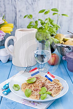 Dutch pancakes with ham for breakfast. Bright colors, blue background. Tasty and caloric. Glass of water and a decanter.