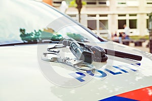 Dutch Police equipment. Handcuffs and phone on top of a police car. Selective focus