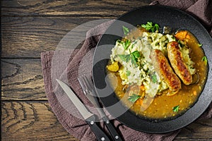 Dutch stamppot of potatoes, kale and sausages with gravy on plate above