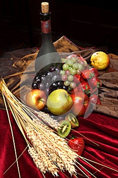 Dutch still life on a velvet tablecloth of juicy fruits, dusty old bottle of wine and ears of wheat, vertical